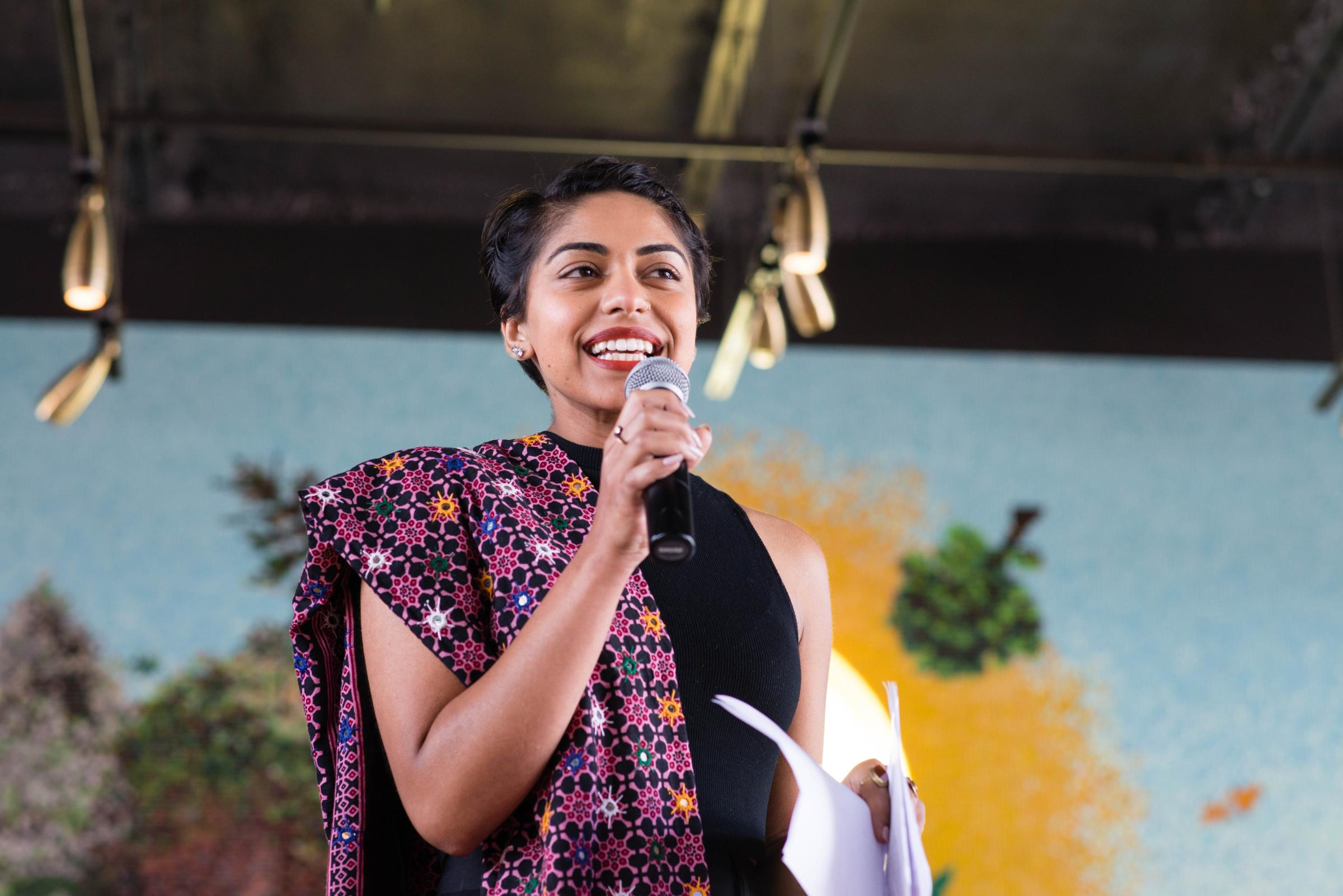 female with purple cloth over shoulder speaking into microphone at the Asian Pacific American Literature Festival