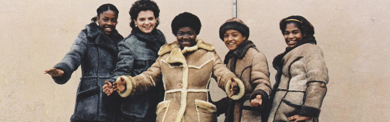 Diverse group of women in coats standing in front of wall